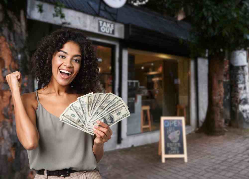Business owner holds cash in front of store